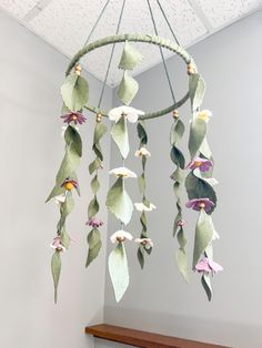 a mobile with flowers hanging from it's side on a shelf in a room