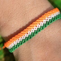 an orange, white and green bracelet on someone's arm