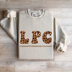 This is the perfect sweatshirt/comfort colors long-sleeve tee for LPC's (Licensed Professional Counselors), LCSW, LMFT, PhD, PsyD, etc. who also love animal prints. Who doesn't love a comfy sweatshirt to spend our weekends and evenings in?  This unique leopard print design will quickly become a favorite for all of your activities such as shopping, reading, and hanging out with friends. Indicate in the personalization section which profession you wish to have displayed on the sweatshirt P R O D U C T   D E S C R I P T I O N .: Made with a medium-heavy fabric blend of 50% cotton and 50% polyester (8.0 oz/yd² (271.25 g/m this sweatshirt feels cozy and is the perfect choice for those colder months. .: The classic fit along with the crew neckline delivers a comfy wearing experience with a clean Custom Print Long Sleeve Cotton Sweater, Long Sleeve Cotton Sweater With Custom Print, Custom Print Long Sleeve T-shirt With Relaxed Fit, Custom Print Long Sleeve Sweatshirt Relaxed Fit, Long Sleeve T-shirt With Custom Print Relaxed Fit, Custom Print Long Sleeve Relaxed Fit Sweatshirt, Long Sleeve Relaxed Fit T-shirt With Custom Print, Casual Long Sleeve Sweater With Custom Print, Marriage Counselor