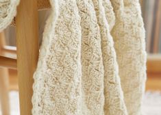 a white crocheted blanket draped over a wooden chair