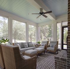 a screened porch with wicker furniture and large windows on the ceiling, along with brick pavers flooring