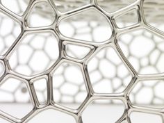 a close up view of an intricate metal object with hexagonal structure in the background