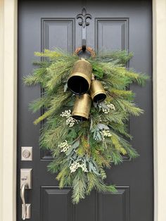 a christmas wreath with bells hanging from the front door and evergreens on the side