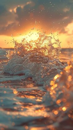 the sun is setting over the ocean with water splashing on it's surface