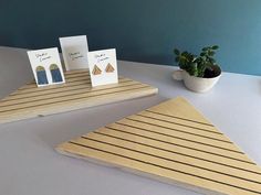 three cards are placed next to each other on a wooden table with a potted plant in the background