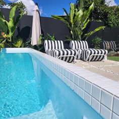 two lawn chairs sitting next to a swimming pool