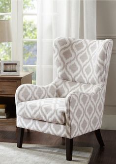 a living room with a white chair and a lamp on the side table in front of a window