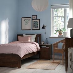 a bedroom with light blue walls and wooden bed frame, pink comforter on the bottom