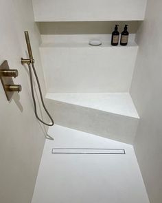 a bathroom with a shower head and two soap dispensers on the wall