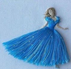 a blue dress is hanging on a white surface with beads and sequins in the shape of a woman's head