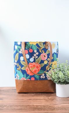 "This tote bag is a great bag to carry every day.  Use it for work, school, shopping, or even as a stylish diaper bag. Bold Floral Tote: ~This bag is made of beautiful Rifle Paper Co canvas fabric featuring a beautiful blue background with a mix of large vintage flowers. ~The bag is reinforced with heavy interfacing, adding extra durability and shape while still being light weight.   ~The base part is made of high-quality faux leather in a nice warm toffee brown. ~Heavy black canvas fabric linin Leather Top Handle Bag With Floral Print, Leather Tote Bag With Floral Print, Floral Print Double Handle Shopping Bag, Elegant Floral Print Tote Bag, Stylish Diaper Bag, Multicolor Floral Print Tote Canvas Bag, Vegan Leather Tote, Flower Bag, School Shopping