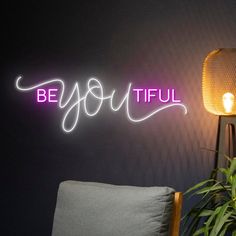 a neon sign that reads be you tiful on the wall next to a chair