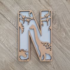 the letter n is made out of wood and has an image of dinosaurs on it