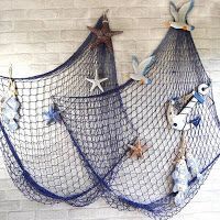 two blue net bags with starfish and seashells hanging on the wall next to each other