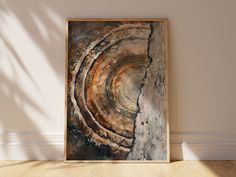 an abstract painting on the wall in a room with wood flooring and white walls