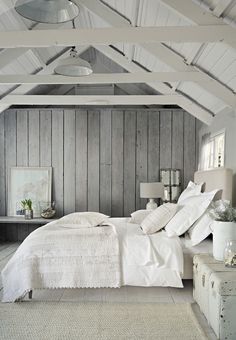 a white bed sitting in a bedroom next to a wooden wall