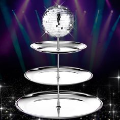 a disco ball sitting on top of two tiered trays with lights in the background