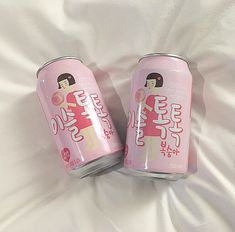 two pink soda cans sitting on top of a bed