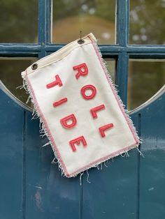 a sign hanging on the side of a blue door that says, roll tide written in red