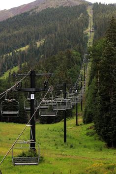 a ski lift going up the side of a mountain with lots of trees on it