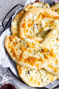 three flat breads with cheese and black pepper sprinkled on them in a bowl