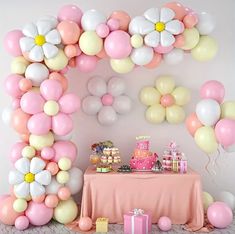 a pink and white birthday party with balloons, flowers, cake and desserts on the table