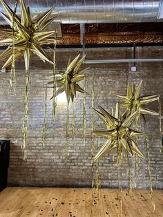 gold stars hanging from the ceiling in an empty room with wooden floors and exposed ceilings