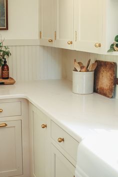 a kitchen with white cabinets and gold handles