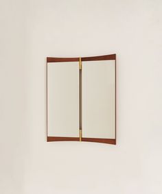 a mirror mounted to the side of a white wall next to a wooden framed object