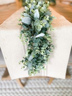 some green plants are on top of a white table cloth and wooden chair leg rest