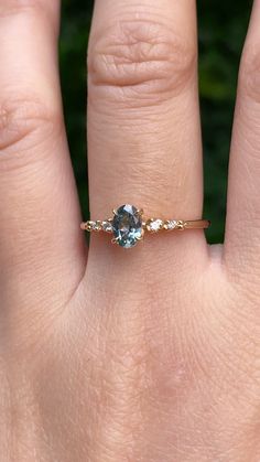 a woman's hand with a ring on it that has a blue stone in the middle