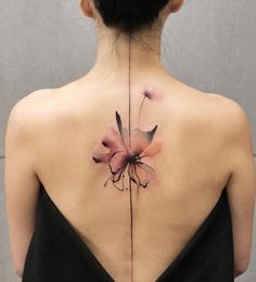 the back of a woman's neck with a flower tattoo on her left side