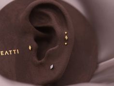 an ear with gold studs on it and the word beati written in gold