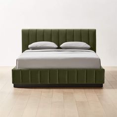 a green bed with two pillows on the headboard and one pillow in the middle