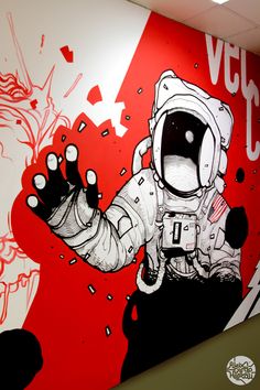 an astronaut painted on the side of a wall in front of a red and white background