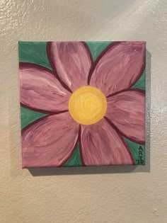 a painting of a pink flower with green leaves on the bottom and yellow center is hanging on a white wall