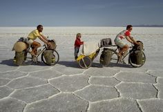 three people riding bikes in the middle of an empty desert