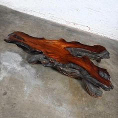 a piece of wood sitting on top of cement floor next to a white brick wall