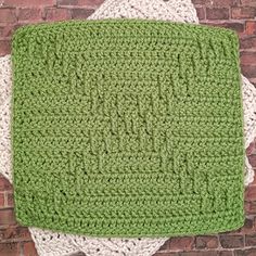 two green and white crocheted placemats sitting on top of each other