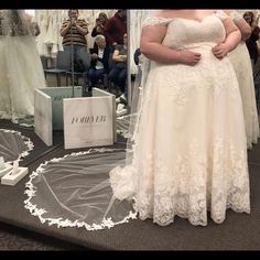 a woman standing in front of a mirror wearing a wedding dress and holding her hands on her hips