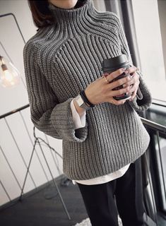 a woman holding a coffee cup in her right hand and wearing a gray sweater on the left