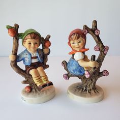 two figurines sitting on top of tree branches