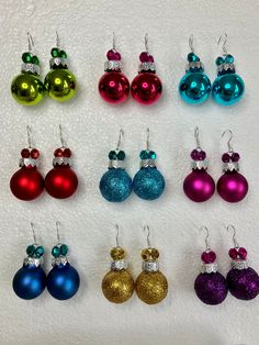 twelve pairs of christmas ornament earrings in various colors and designs on white background