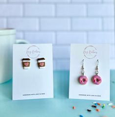 two earrings with donuts on them are sitting next to each other in front of a card