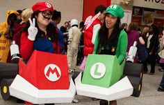 two women dressed up as mario and luigi from mario kart are standing in front of a store