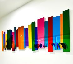 an art piece is hanging on the wall in front of a white wall with multiple colored panels