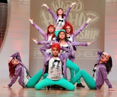 a group of young people standing on top of each other in front of a stage