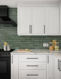 a kitchen with white cabinets and green tile backsplash, black stove top oven