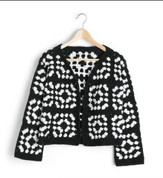 a black and white knitted jacket hanging on a hanger