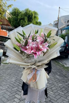 a woman holding a bouquet of flowers on top of a brick road in front of a building